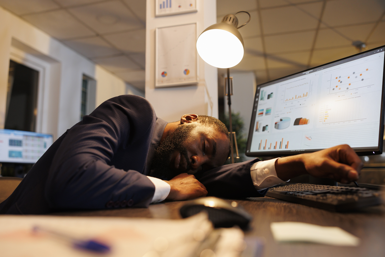 Homem dormindo sobre sua mesa de trabalho