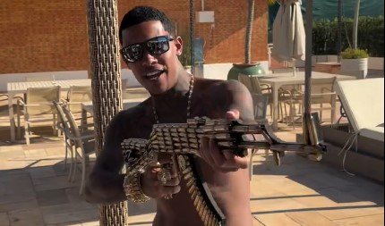 Foto MC Poze posa com réplica de fuzil dada por influenciador ex-bolsonarista