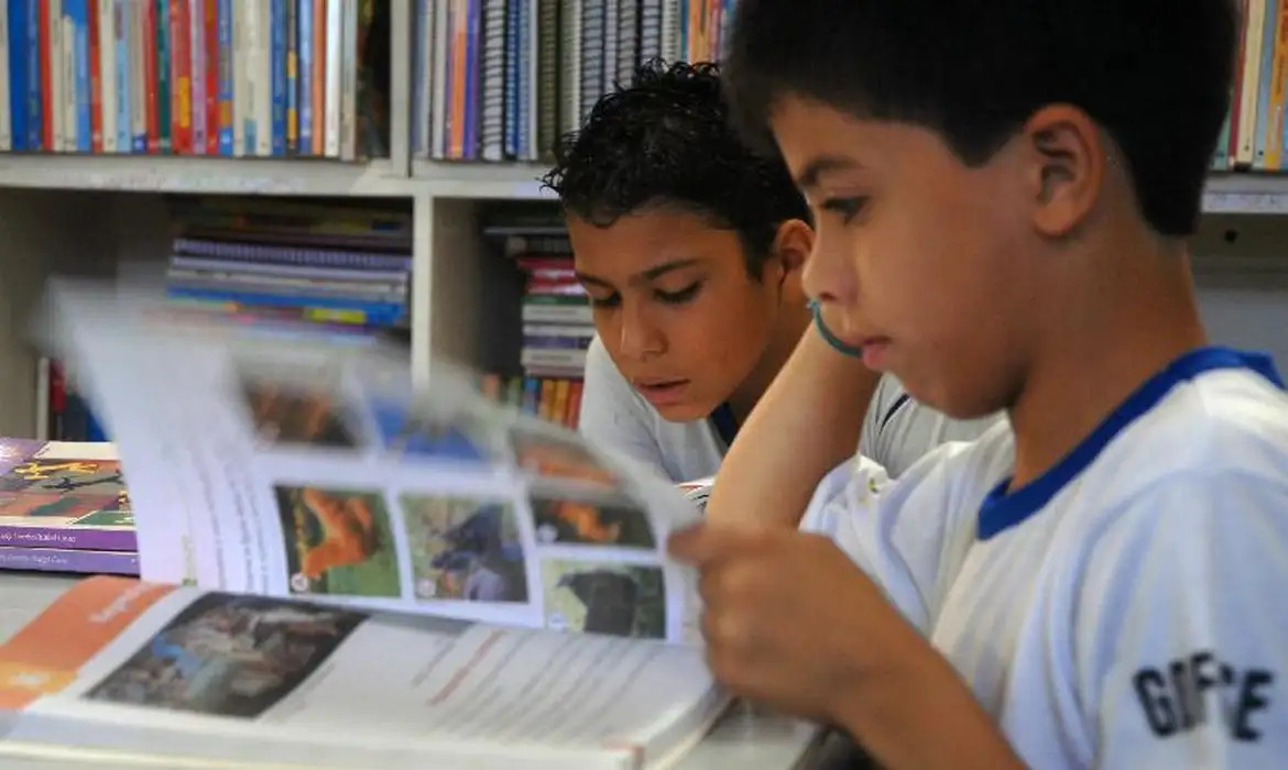 Crianças lendo livro didático